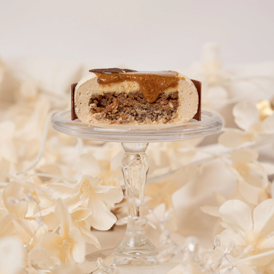 Slice of cake on a small glass stand with a white floral background